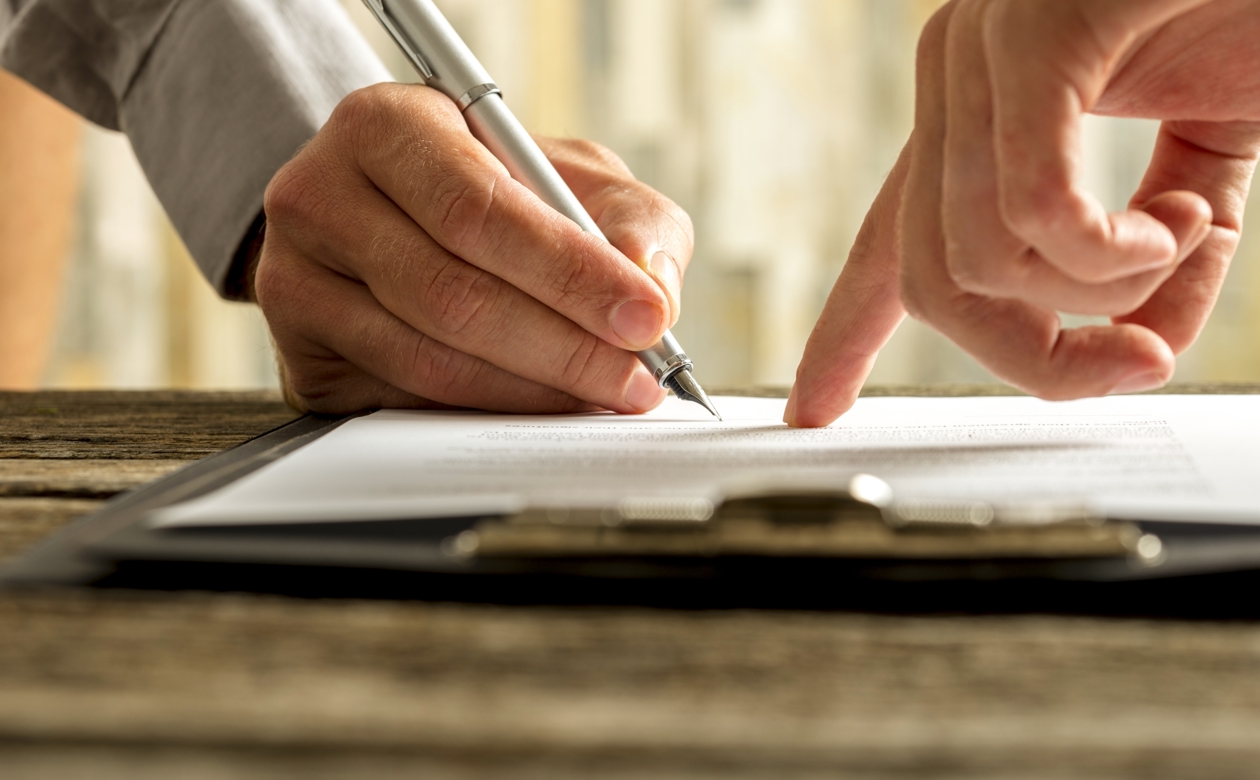 Hænder der skriver under på dokument