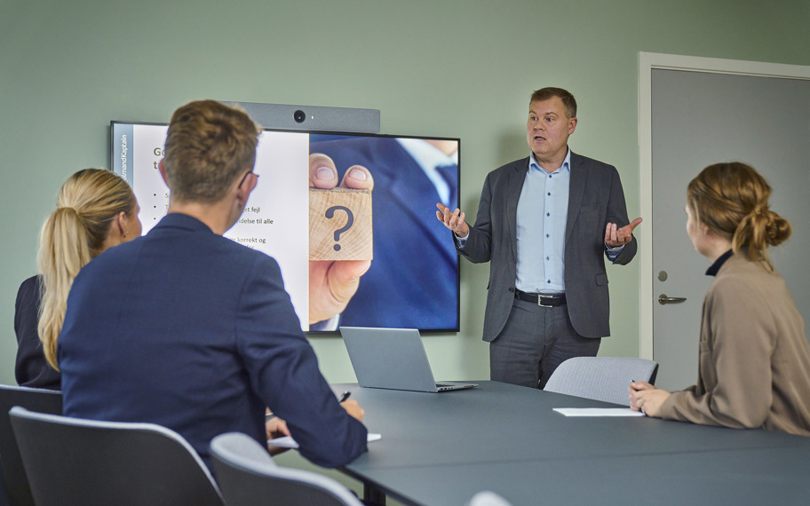 Mand afholder møde og præsenterer foran tre personer