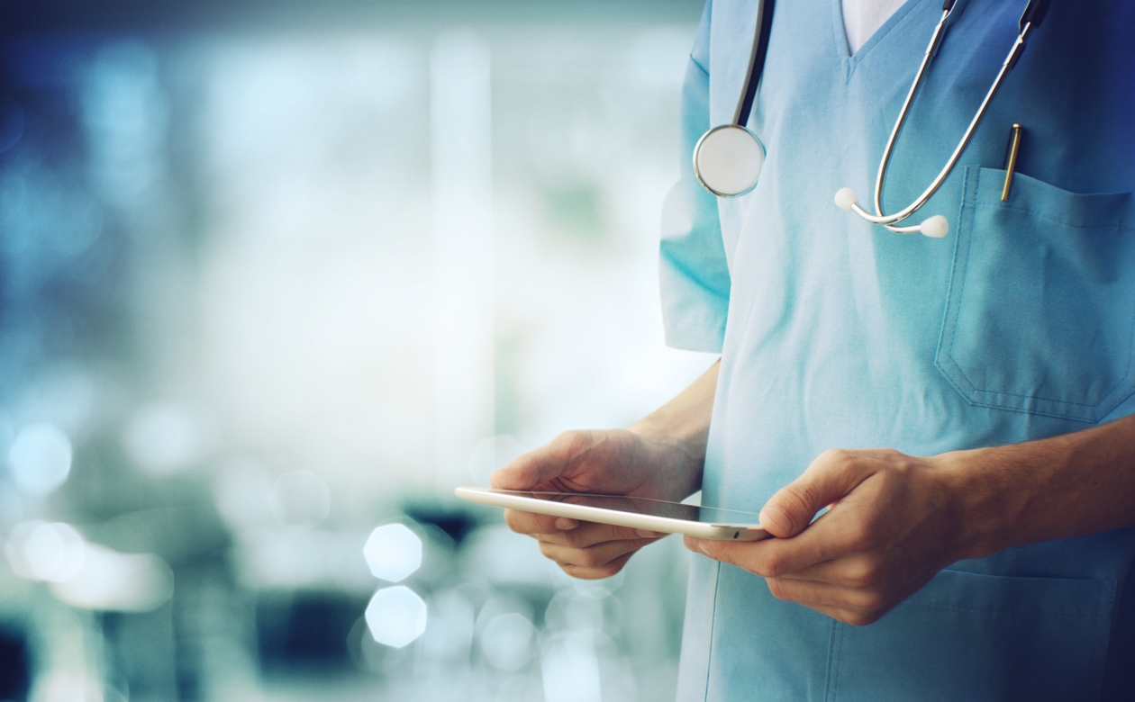 Læge står med ipad i hænderne