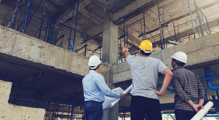 Tre personer taler på byggeplads