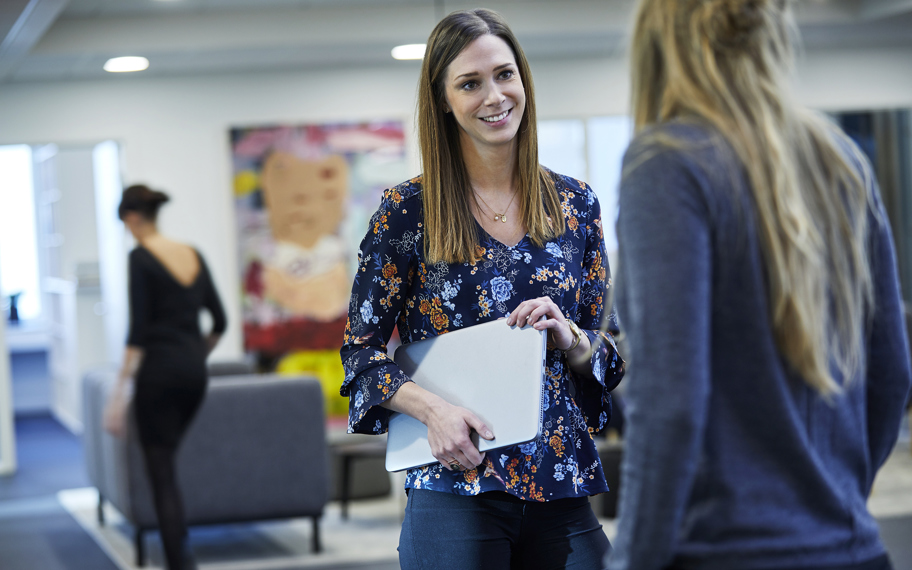 Mette Myrup med bærbar computer under armen snakker med kvinde