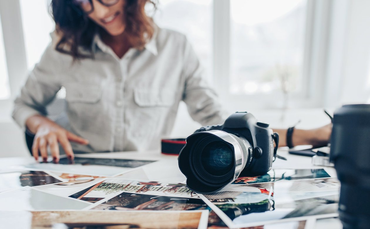 Kvinde foran kommercielle personbilleder på bord med kamera