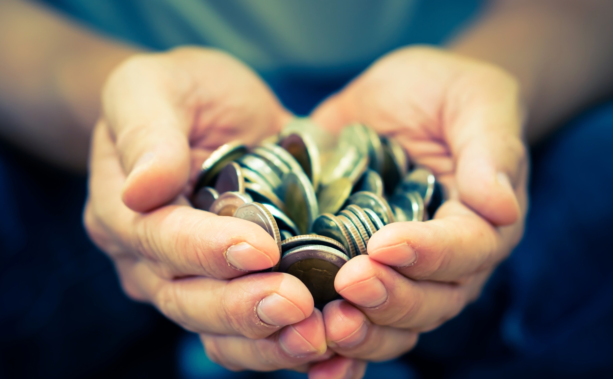 En masse mønter i hænder på person