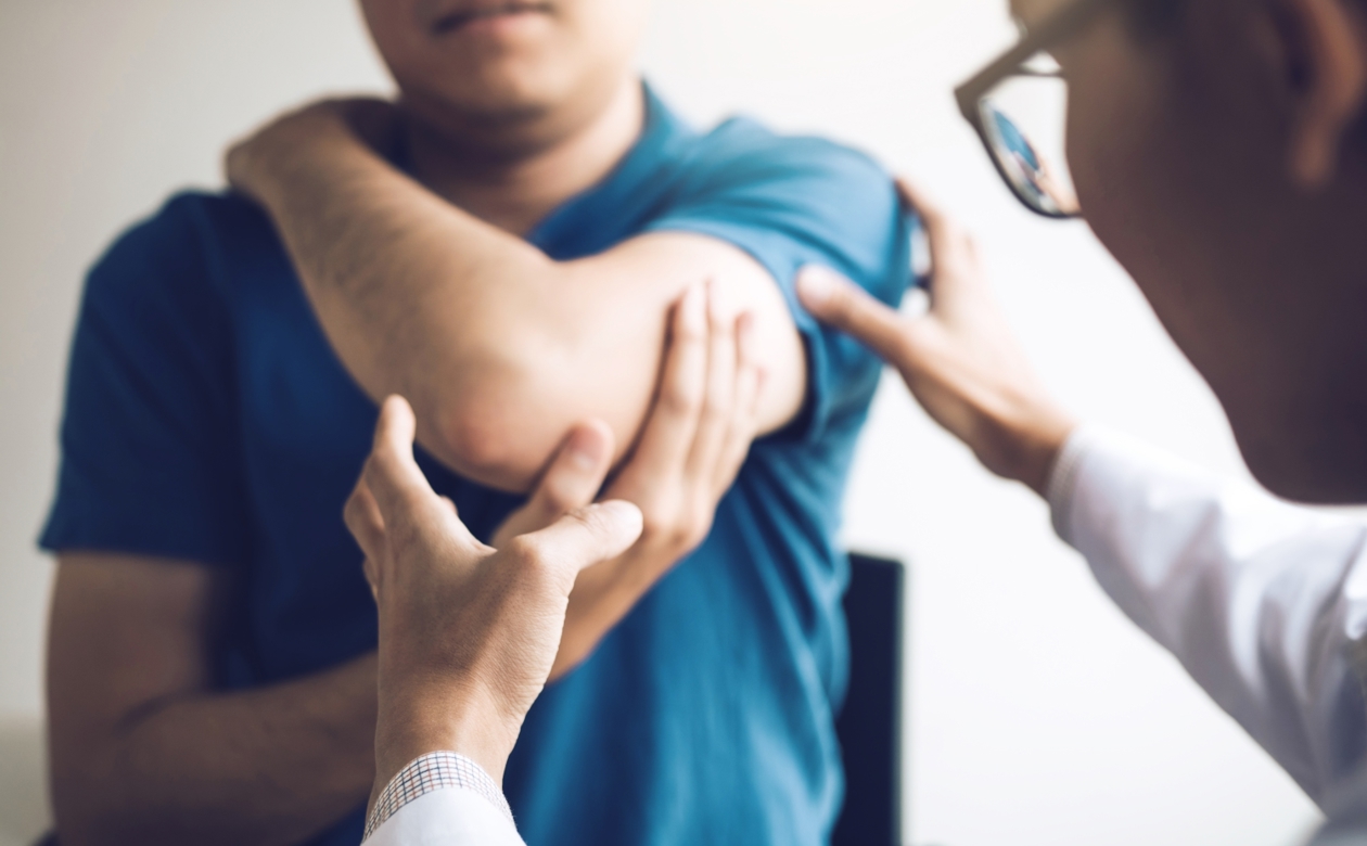 Læge der kigger på en arm eller albue ved en erstatning