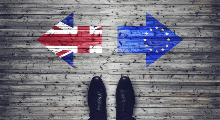 Person står overfor to pile på gulvet med EU flaget i det ene og det britiske i den anden