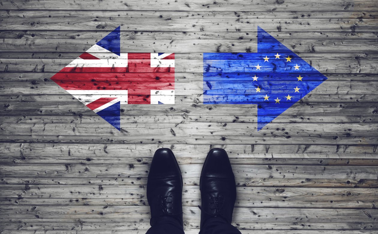 Person står overfor to pile på gulvet med EU flaget i det ene og det britiske i den anden