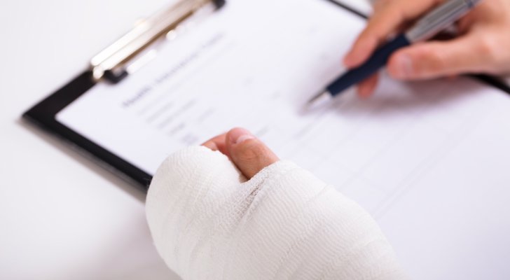 Person med hånden i gips underskriver papirer om arbejdsskade