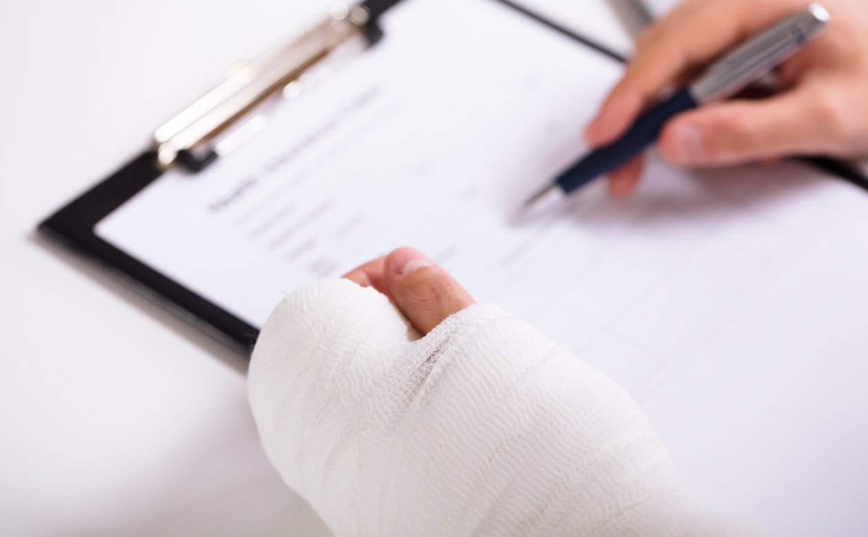 Person med hånden i gips underskriver papirer om arbejdsskade