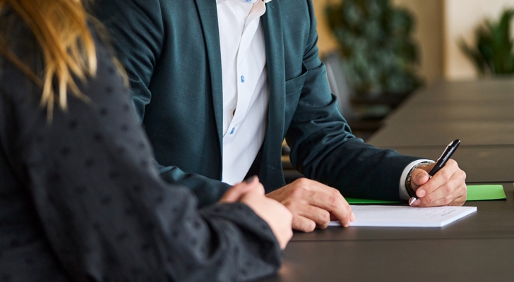 To personer i møde, hvor der bliver skrevet ned på papir af den ene