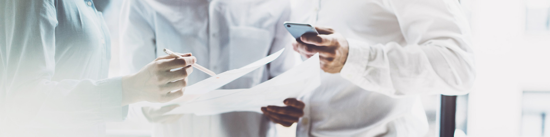 Tre personer står med papirer