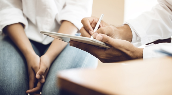 Lægekonsultation hvor læge skriver på ipad