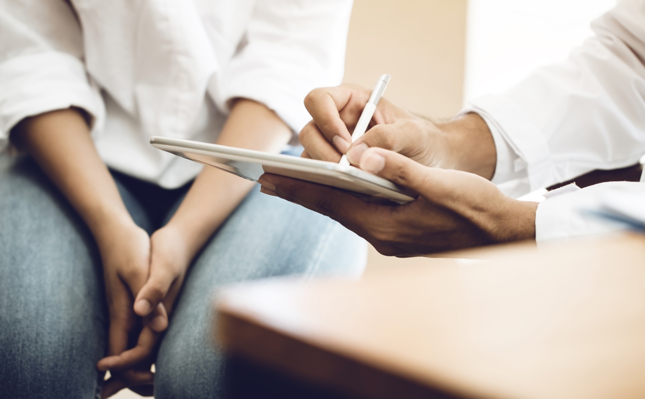 Lægekonsultation hvor læge skriver på ipad