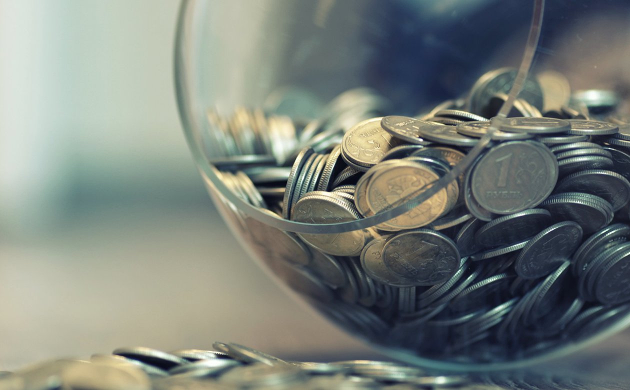 Mønter i glasbowle som er væltet