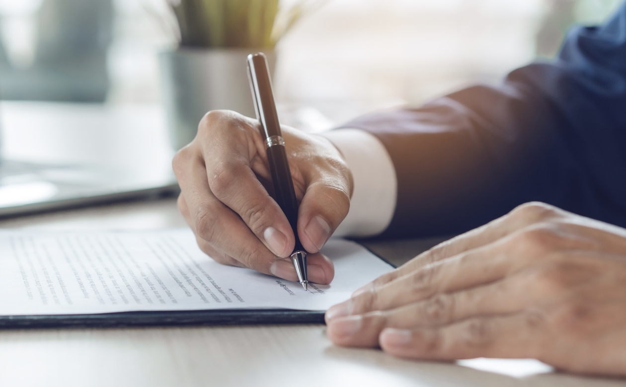 Person underskriver kontrakt med kuglepen