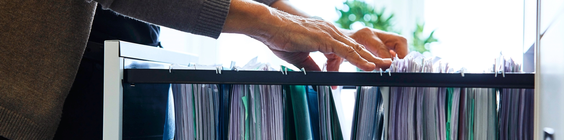 Person kigger efter sagsmappe i skuffe