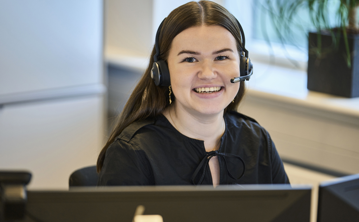 Advokatsekretær siddende ved computer med headset