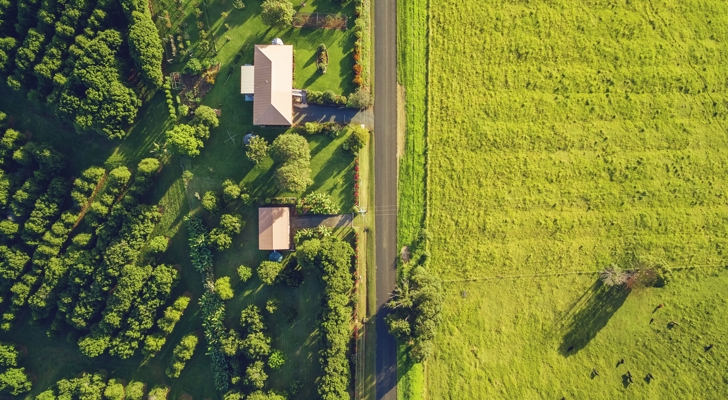 Ejendom ved landevej og grøn mark fra fulgeperspektiv 