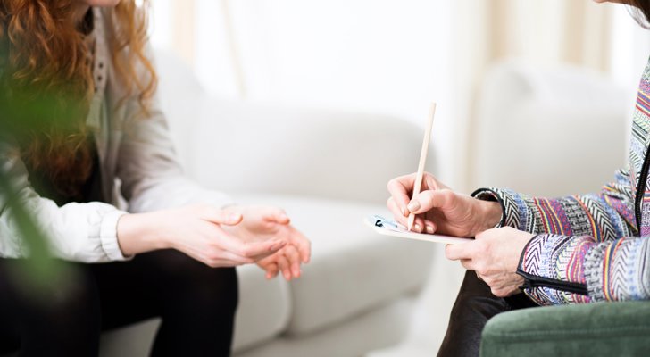 To kvinder sidder og taler over aftale, hvor den ene skriver ned på papir