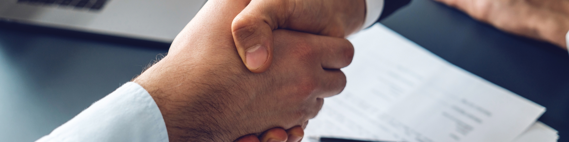 Håndtryk på aftale med kontrakt liggende under