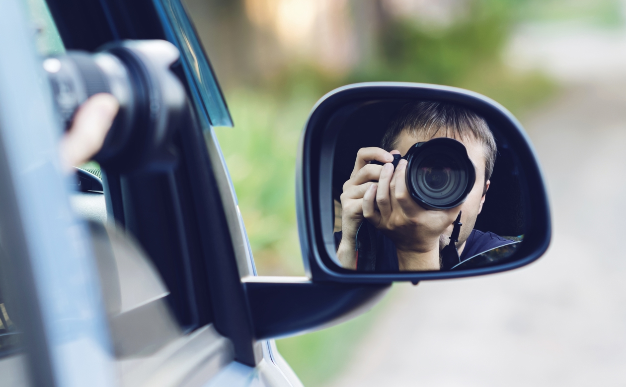 Person sidder i bil og overvåger med kamera