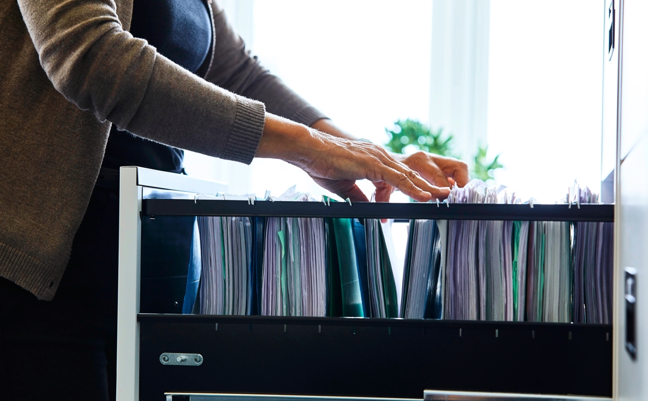 Person kigger efter sagsmappe i skuffe