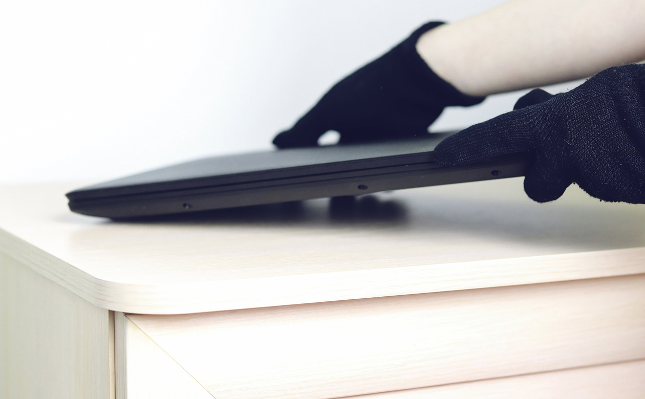 Person med sorte handsker stjæler bærbar