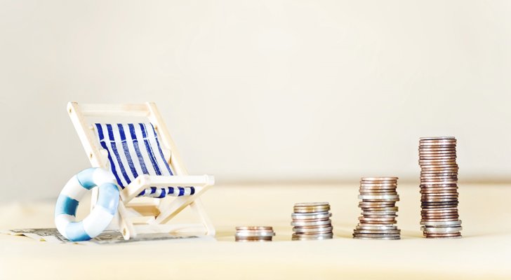 Stakke af mønter med lille strandstol med siden af - feriepenge