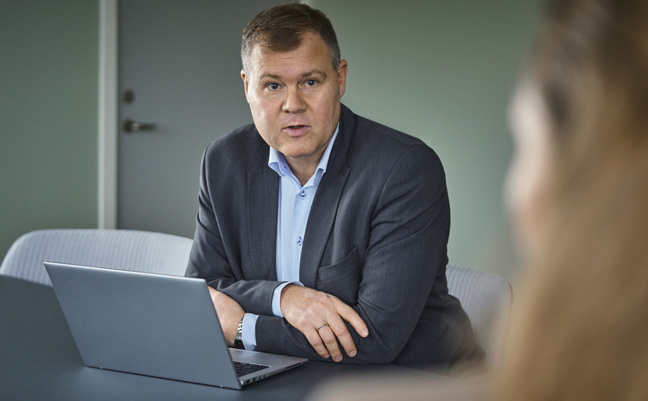 Jens Baagøe Thomsen siddende ved bærbar og snakker med kvinde