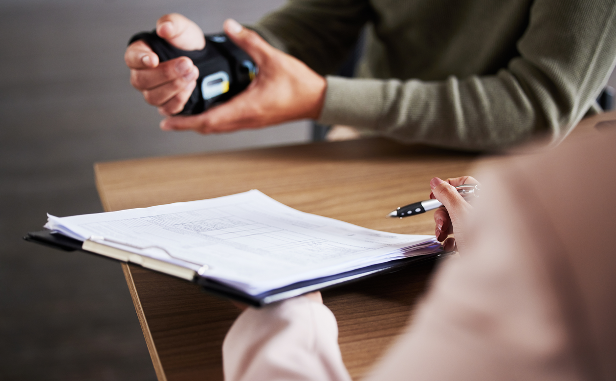 Mand sidder med hånd i skinne og holder møde med person omkring arbejdsskadeerstatning