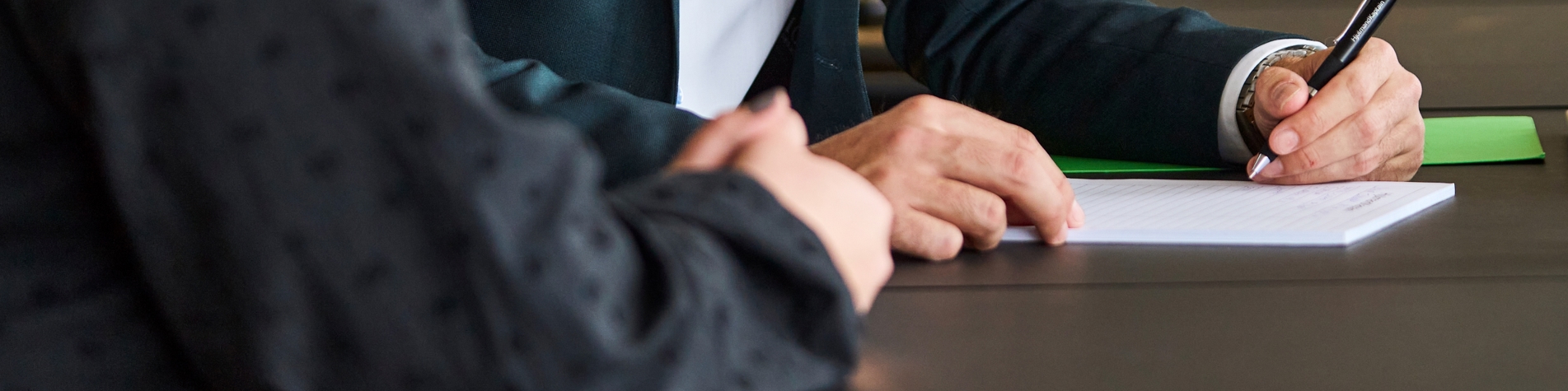 To personer i møde, hvor der bliver skrevet ned på papir