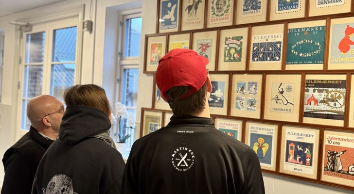 Karsten Madsen og to personer på julemærkehjemmet kigger på billedevæg