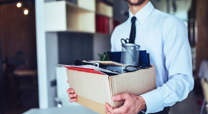 Person der fratræder sin stilling med alle sine kontorartikler i kasse