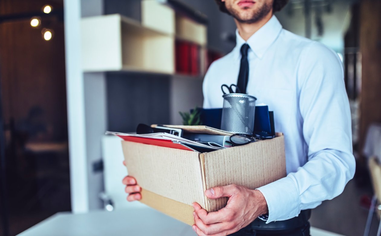 Person der fratræder sin stilling med alle sine kontorartikler i kasse