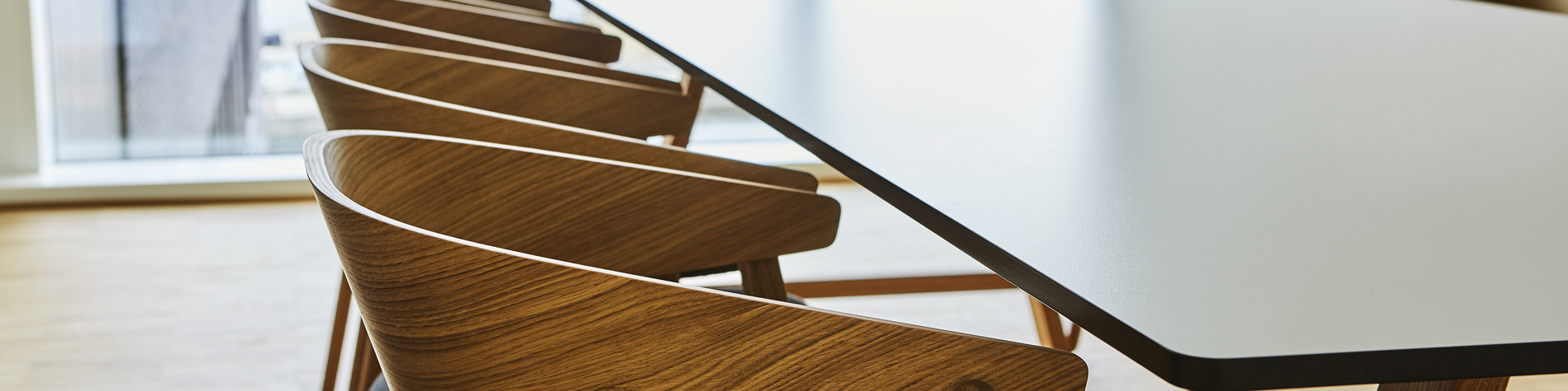 Et tomt mødelokale med et langt bord og stole