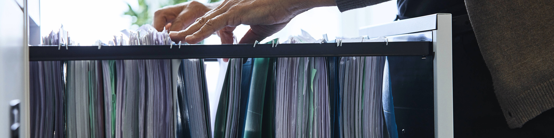 Person kigger efter sagsmappe i skuffe