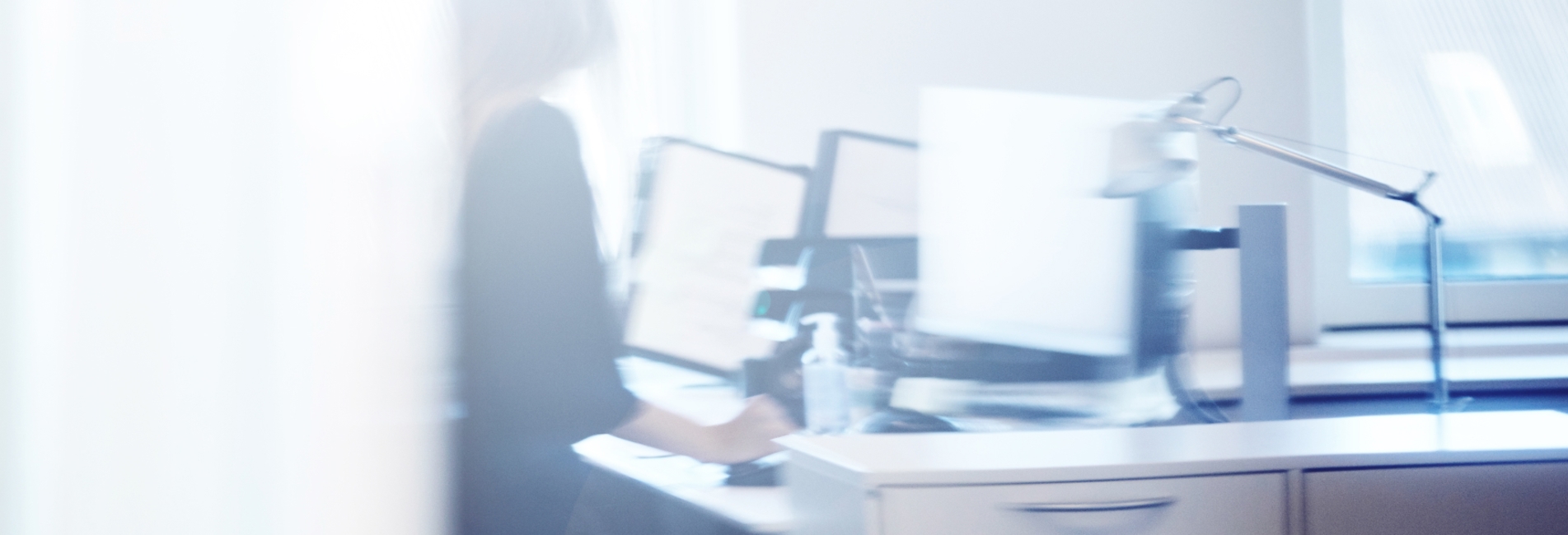 Person sidder ved skrivebord foran computer