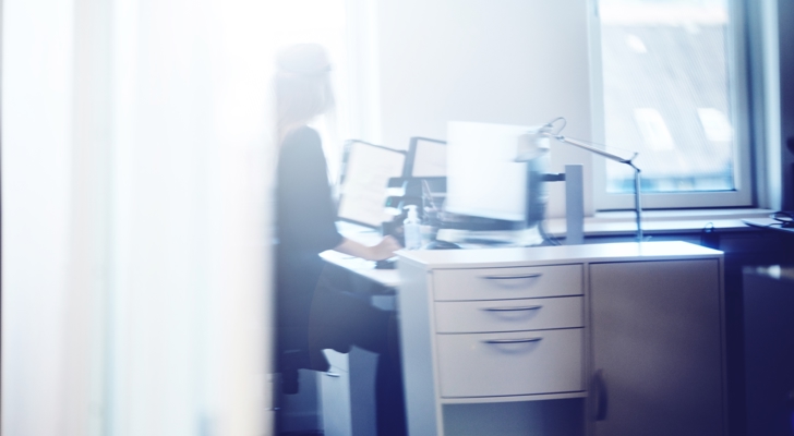 Person sidder ved skrivebord foran computer