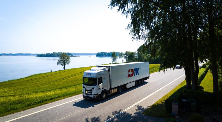 Lastbil på landevej med DTK logo på siden