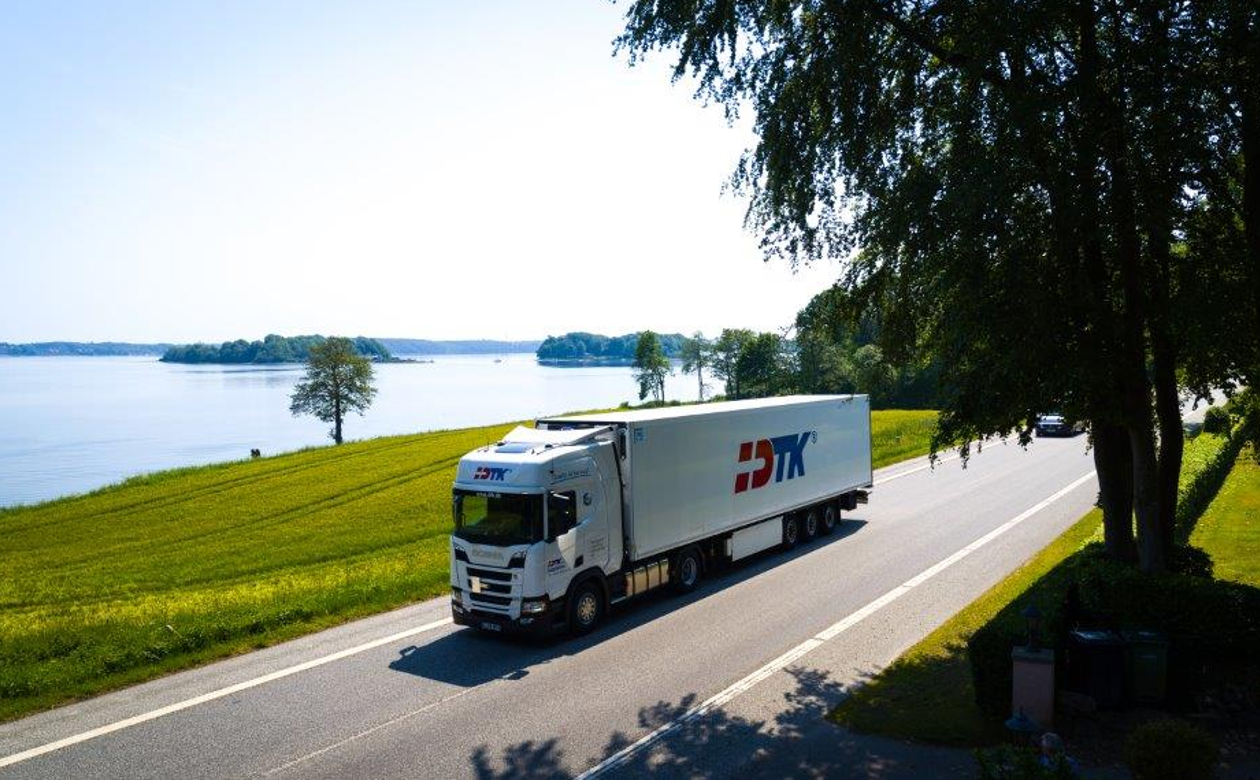 Lastbil på landevej med DTK logo på siden