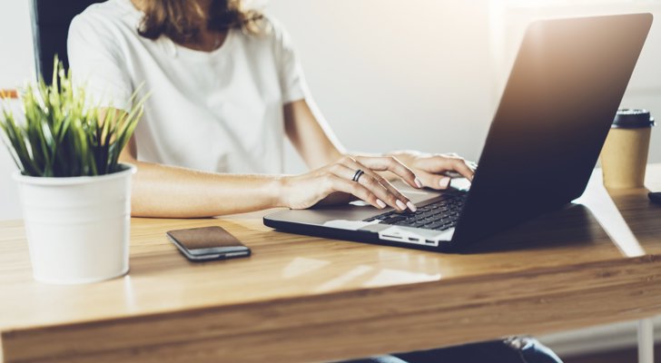 Kvinde sidder ved bærbar ved sin hjemmearbejdsplads