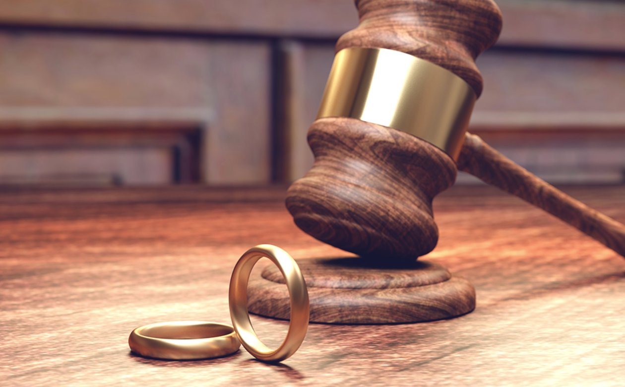 Skilsmisse symboliseret ved to vielsesringe og dommerhammer i baggrunden
