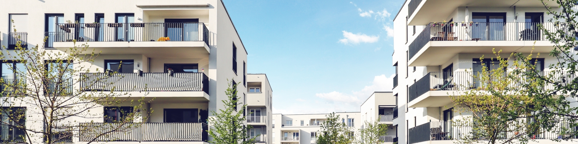 Lejligheder udefra med grønne træer og buske